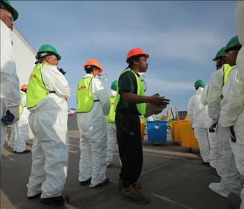 Crew Members in white protective suits standing in parking lot